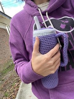 a woman in a purple hoodie holding a crocheted cup