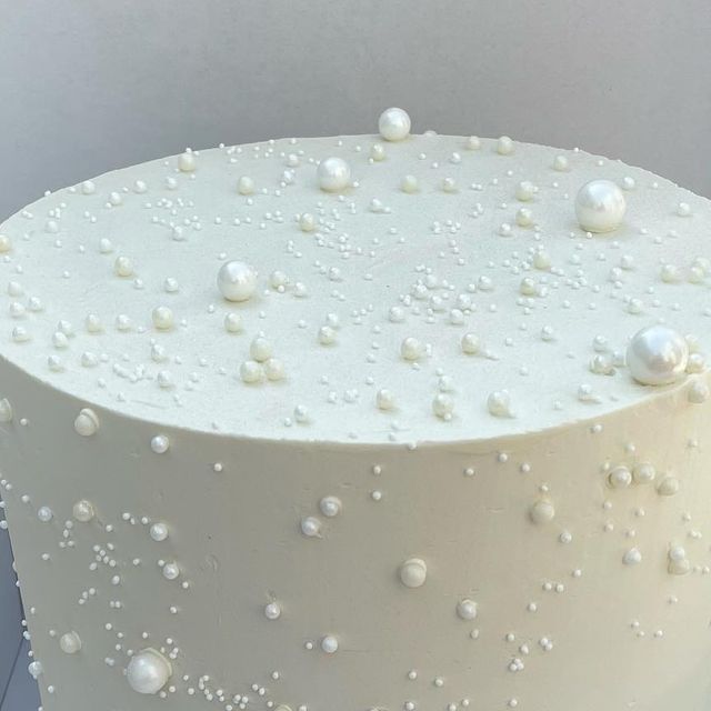 a close up of a white cake with pearls on it