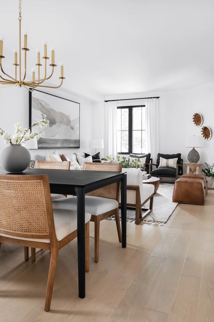 a living room filled with furniture and a chandelier above a wooden dining table