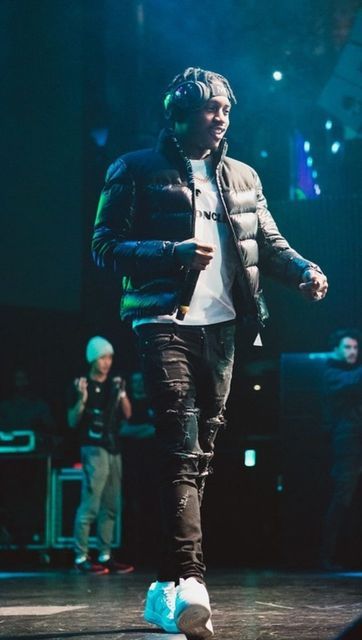 a man is walking on the stage with headphones in his ears and wearing a jacket