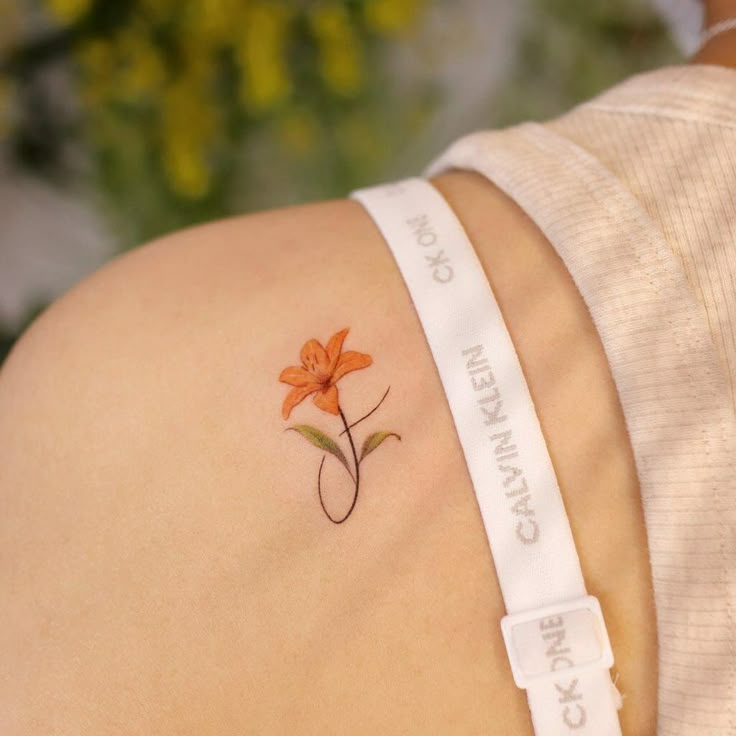 a small tattoo on the back of a woman's left arm with an orange flower