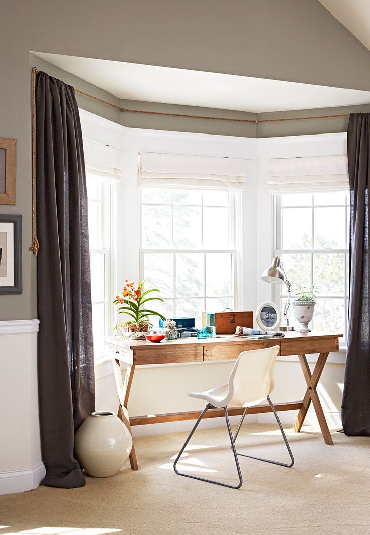 a room with two windows and a desk in the corner, along with a pair of chairs