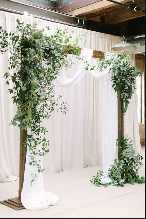 an indoor ceremony with white drapes and greenery