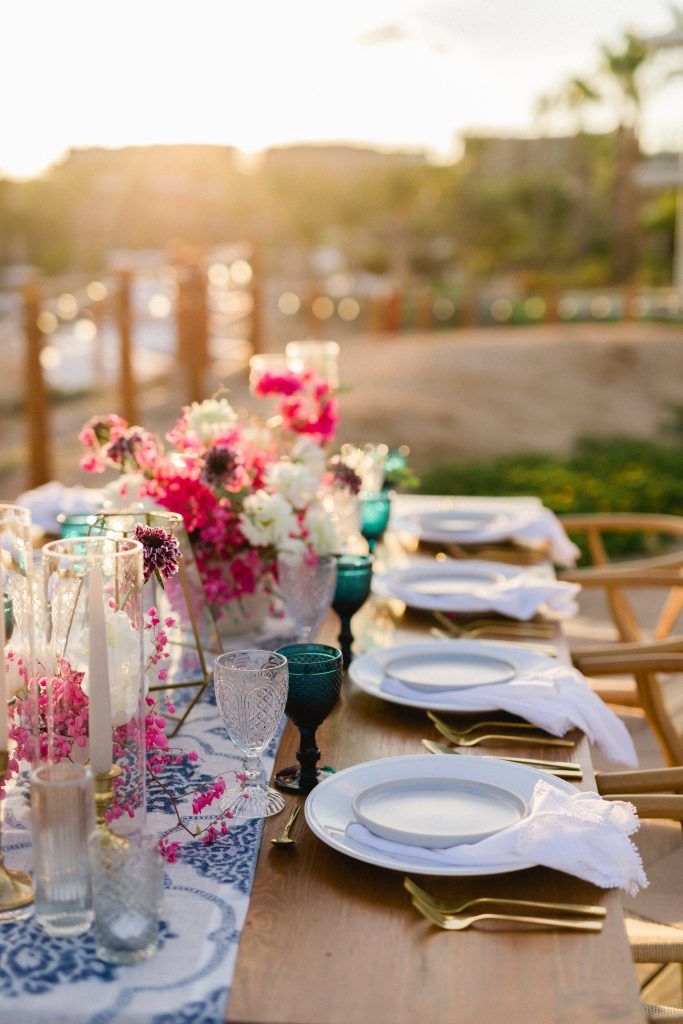 a long table with plates and vases filled with flowers