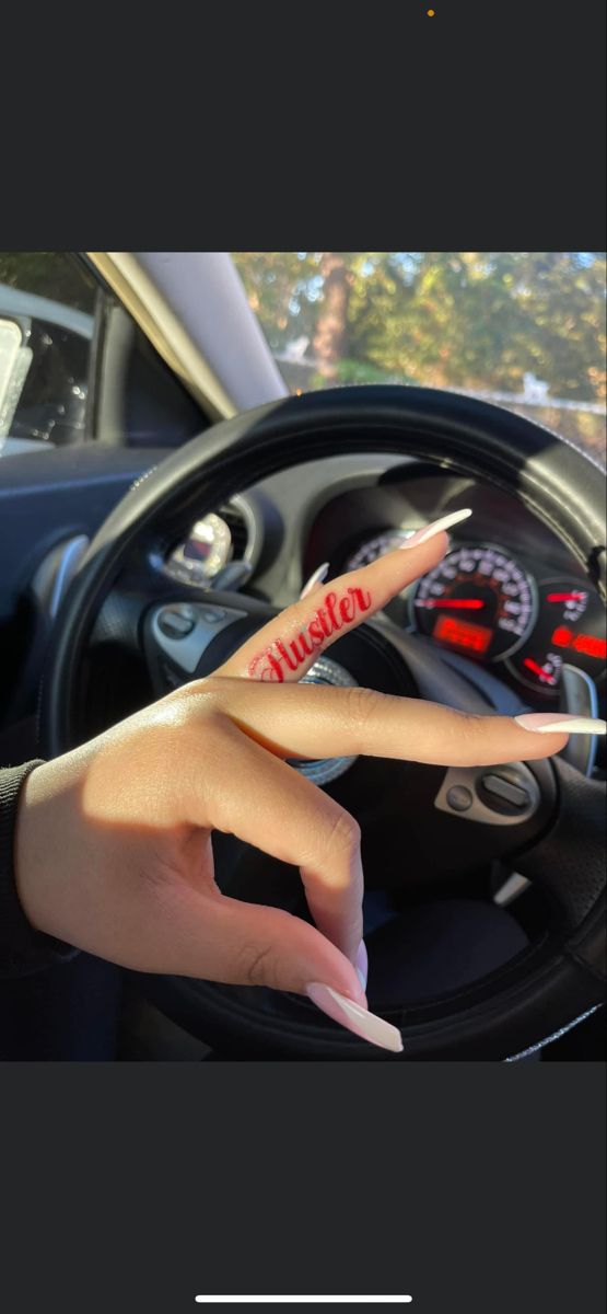 a woman's hand is on the steering wheel of a car with her fingers up