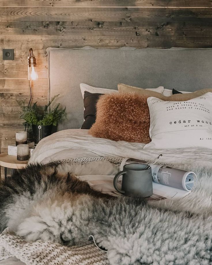 a bed that has some pillows and blankets on top of it, next to a lamp