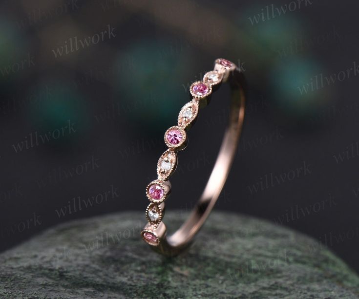 a pink diamond ring sitting on top of a rock