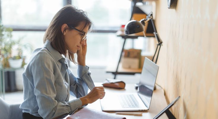 a woman sitting at a desk with a laptop computer and notebook in front of her