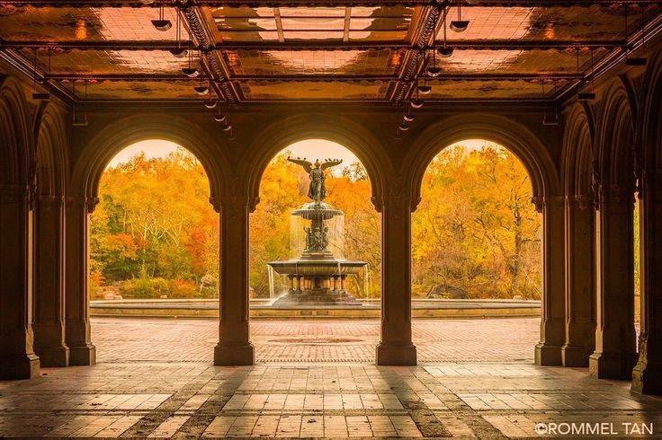 an open courtyard with arches and a fountain in the center, surrounded by autumn foliage