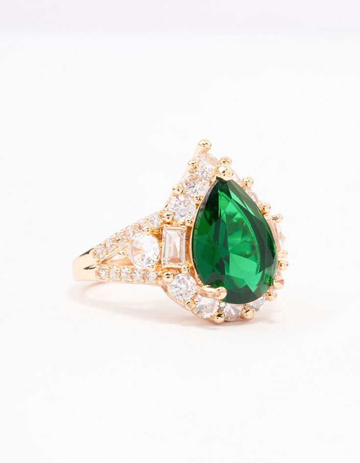 an emerald and diamond ring with two pear shaped diamonds on the side, set in yellow gold