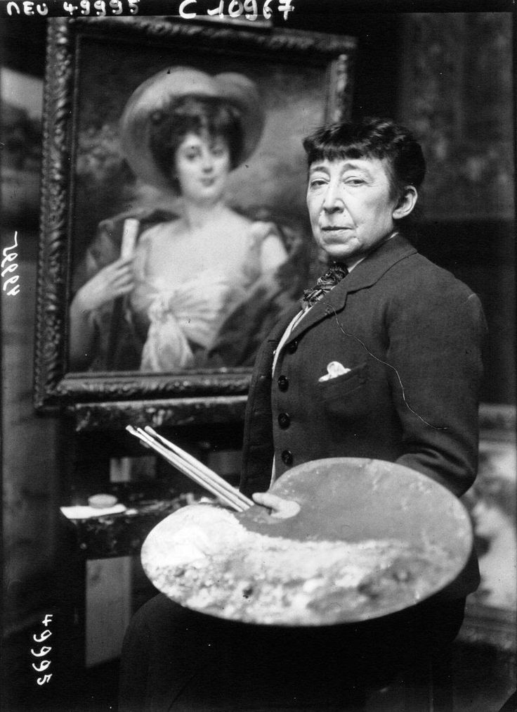 an old black and white photo of a woman holding a paintbrush in front of a painting