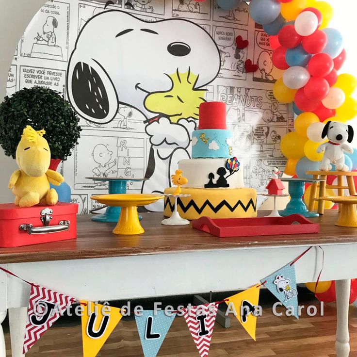 a table topped with lots of balloons and cake next to a wall covered in cartoon characters