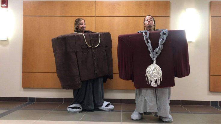 two people standing next to each other in front of a wall with clothing hanging on it