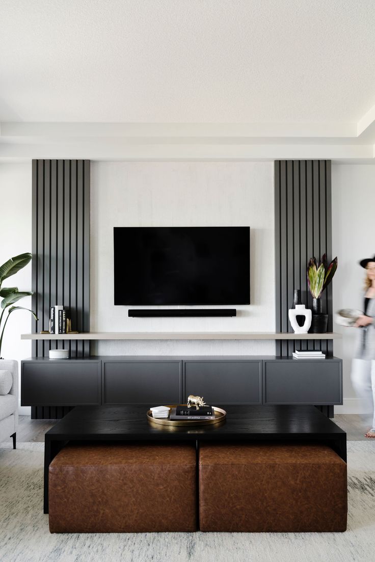 a woman standing in front of a flat screen tv mounted on a wall above a coffee table