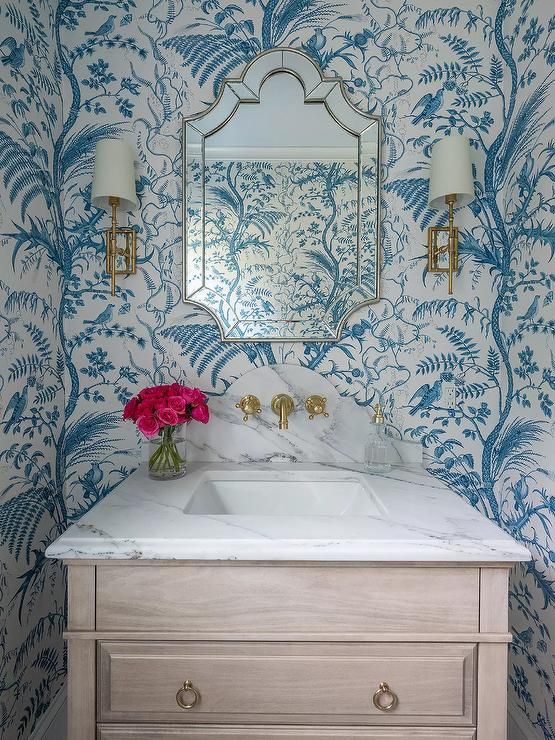 a bathroom with blue and white wallpaper and a mirror on the wall above it