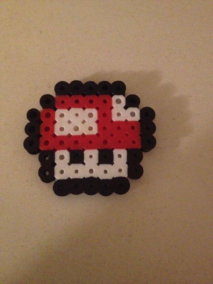 a red and white mushroom brooch sitting on top of a table next to a wall