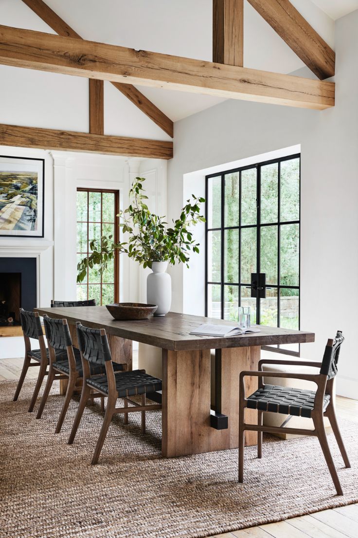 a dining room table with chairs and a potted plant in the center, next to a fireplace