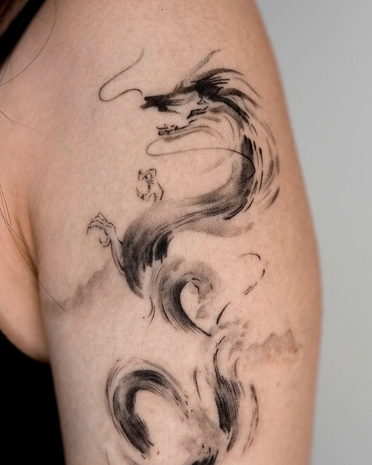 a woman's arm with an artistic tattoo design on the back of her shoulder