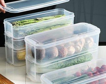 three plastic containers filled with food on top of a white counter next to a cutting board