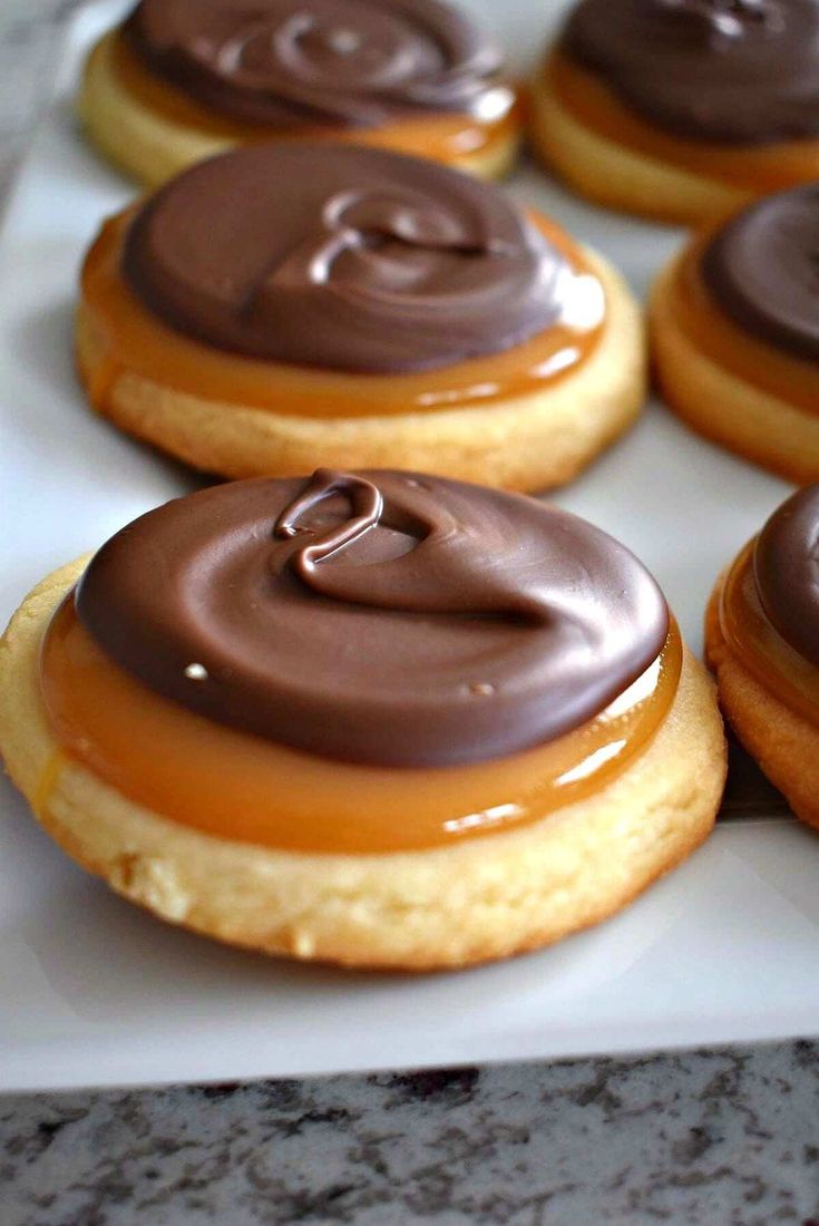 chocolate frosted donuts sitting on top of a white tray covered in icing