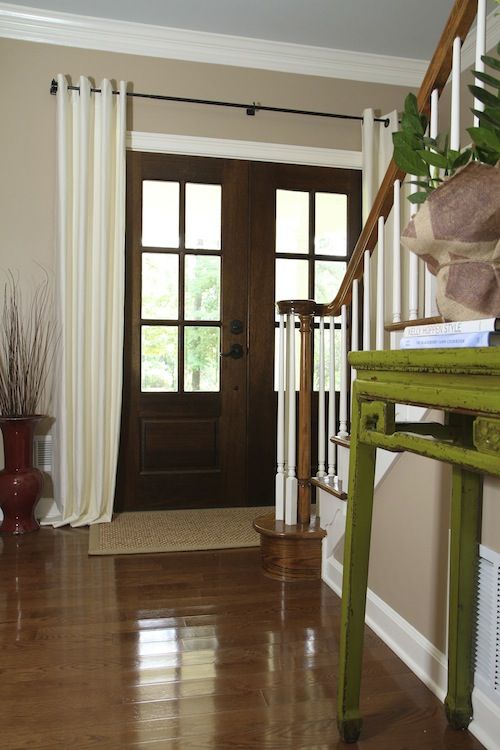 a green table sitting in the middle of a living room next to a wooden door