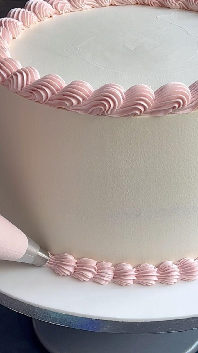 a large white cake with pink icing and a spatula on the top is ready to be cut