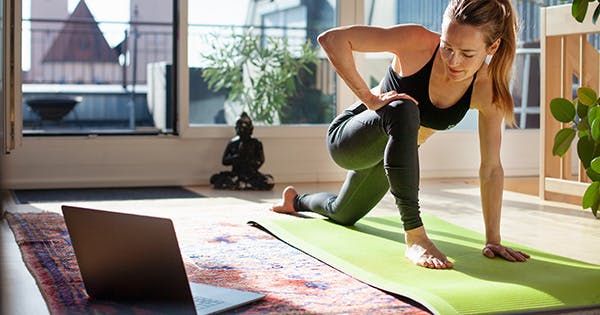 a woman is doing yoga in front of a laptop