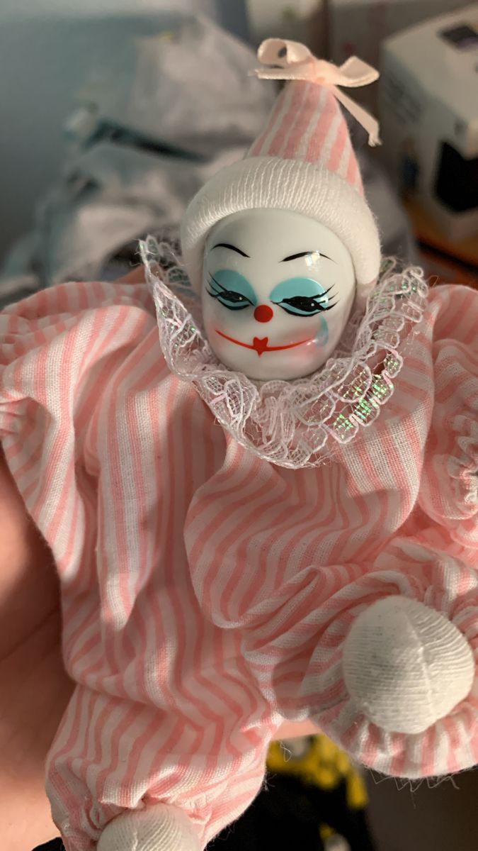 a doll is wearing a pink and white striped dress with a clown face on it