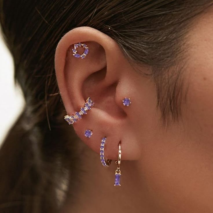 a close up of a person wearing ear piercings with blue stones on the outside of their ears