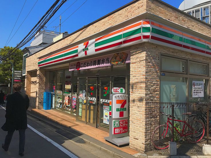 a man walking down the street in front of a small store with bicycles parked outside