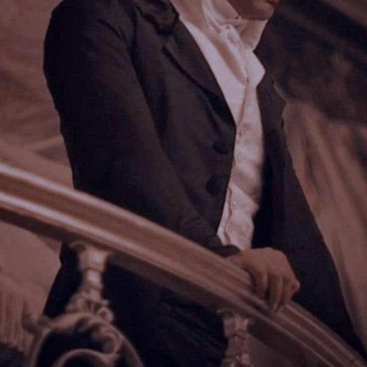 a man in a tuxedo and bow tie standing next to a stair case