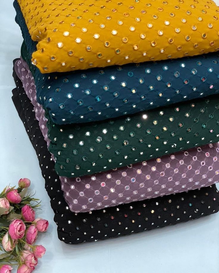 six different colored fabrics stacked on top of each other with flowers in the background and one folded