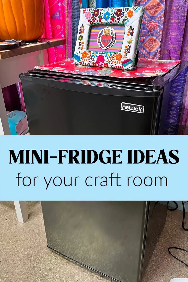 a mini fridge sitting on top of a floor next to a table with a bag on it