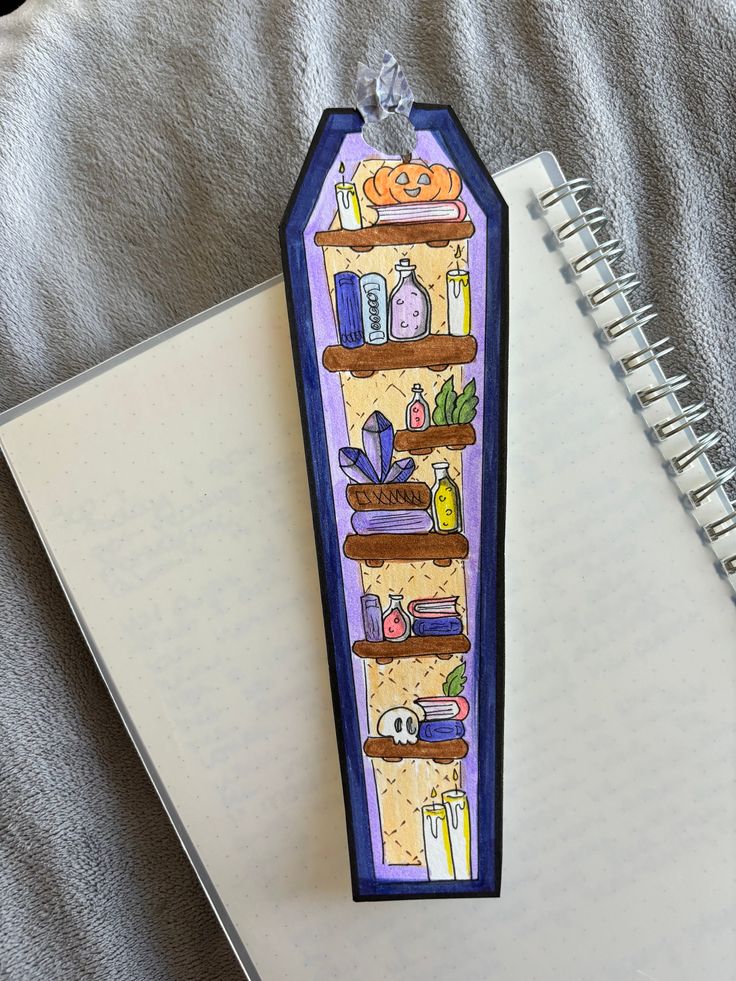 a bookmark with an image of shelves and pumpkins on it next to a notebook