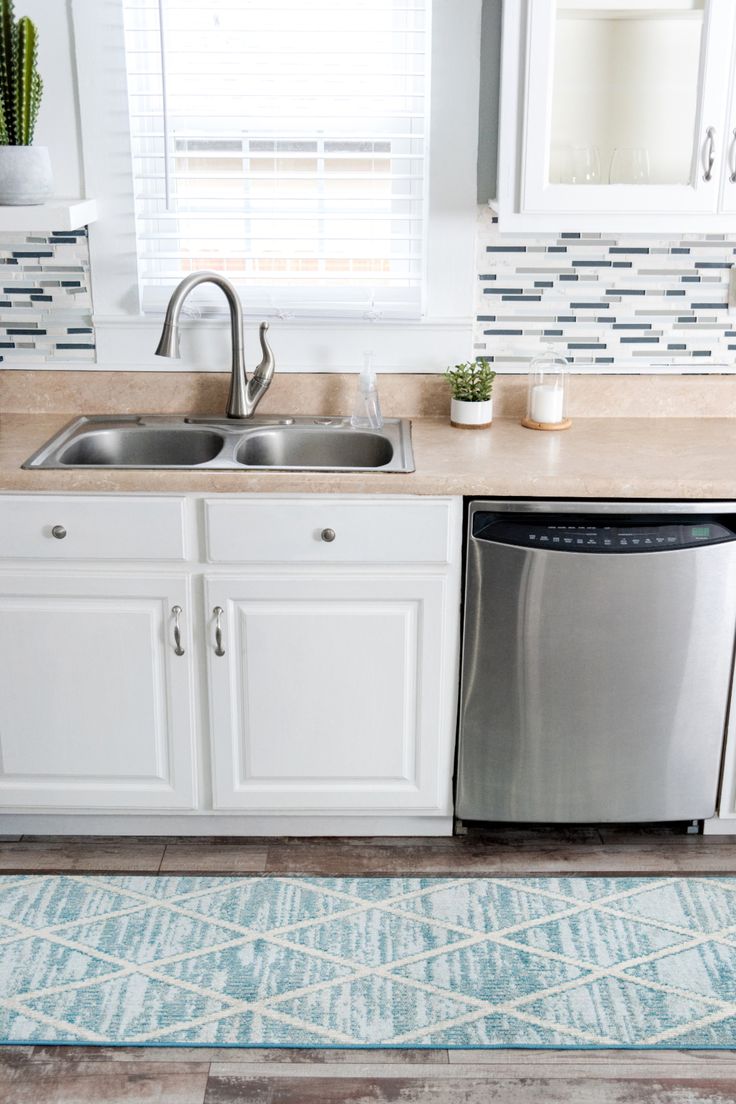 a kitchen with white cabinets and stainless steel dishwasher