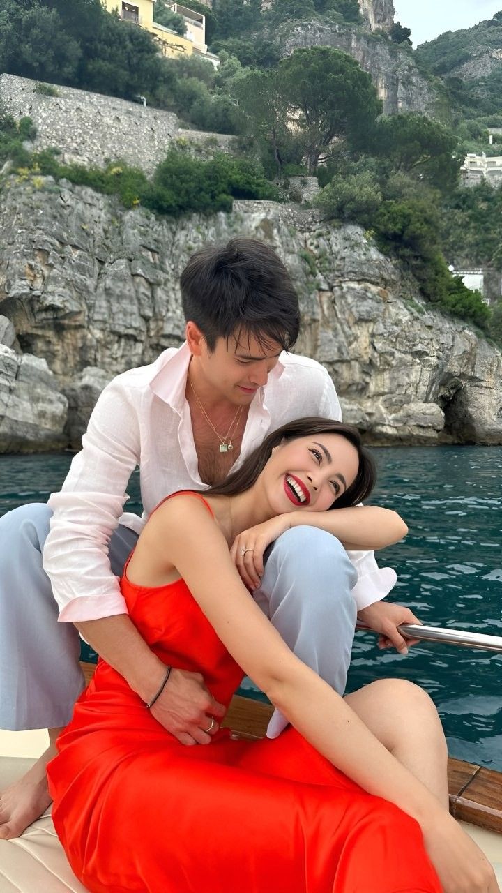 a man and woman sitting on top of a boat in the water next to each other