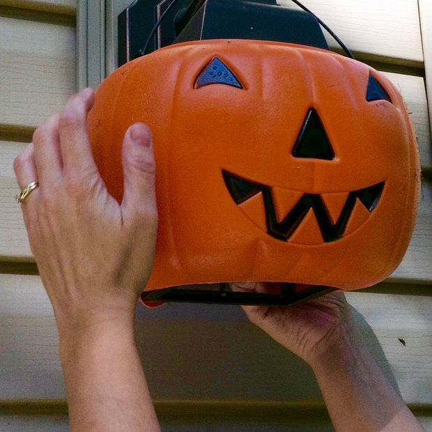 a person holding an orange jack - o - lantern in front of a house