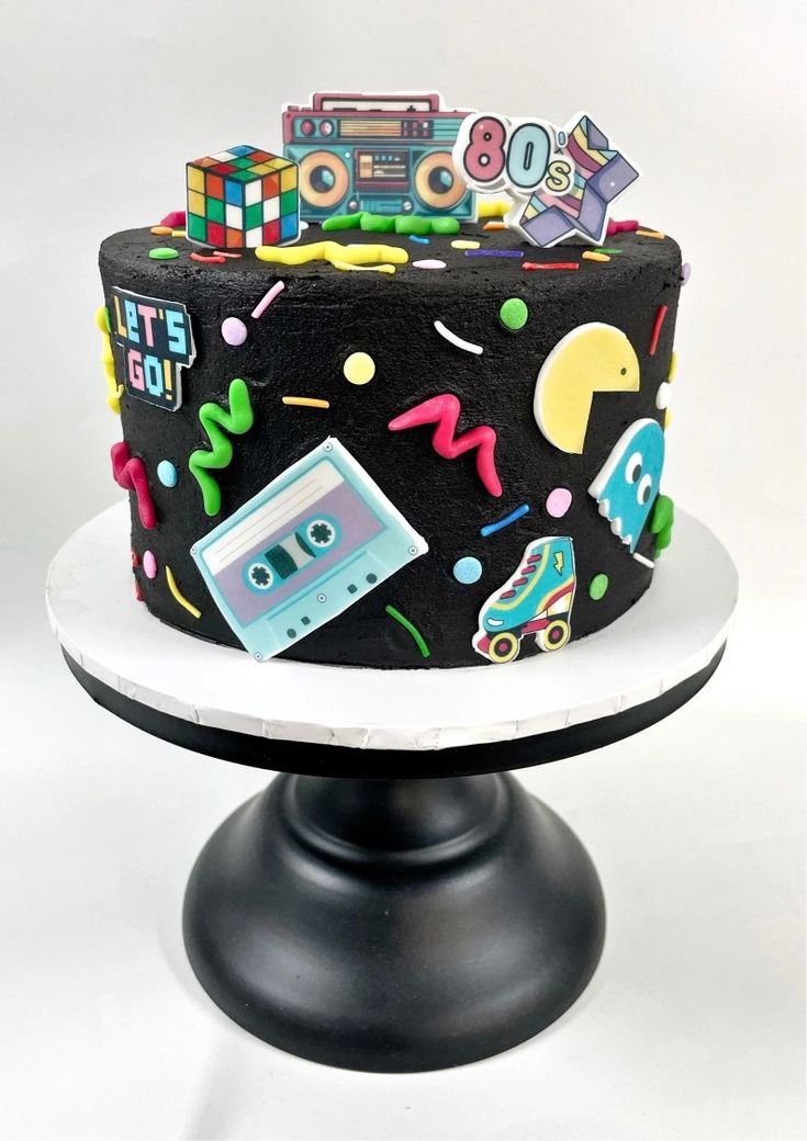 a birthday cake decorated with cassette tape recorders and other items on a plate,