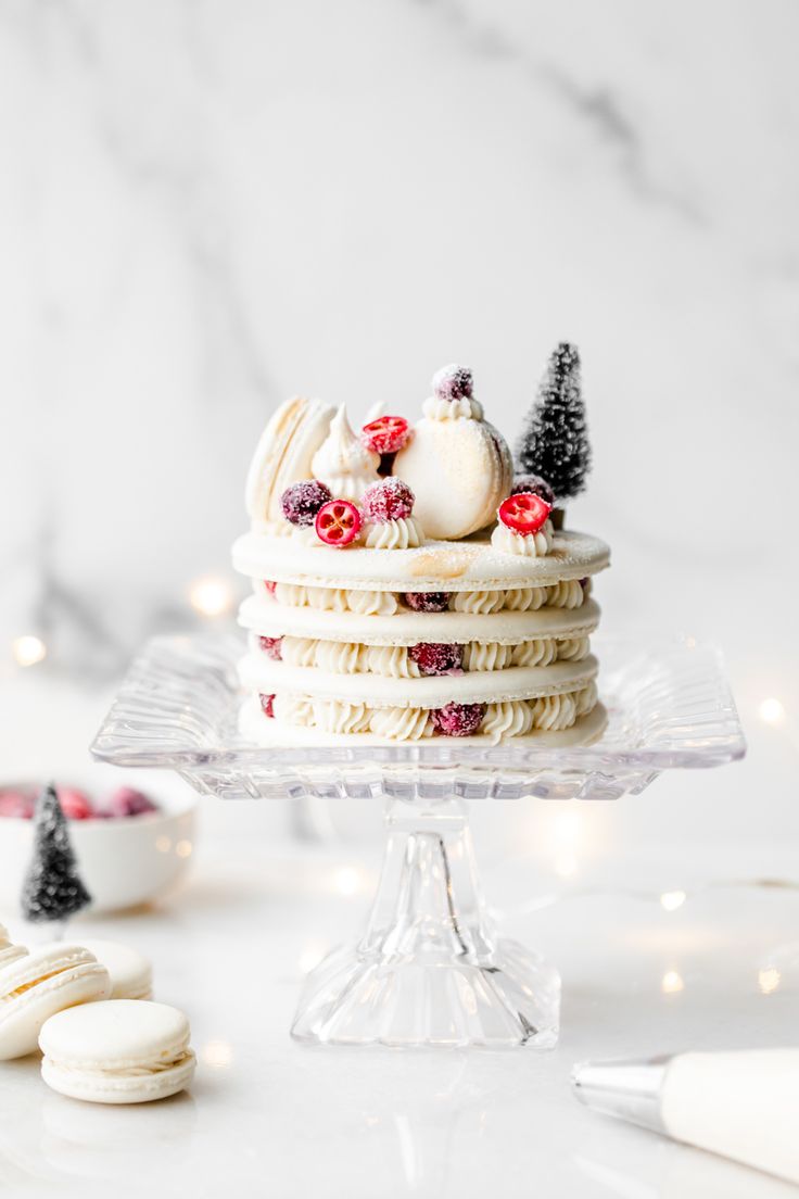 a cake with white frosting and berries on top sitting on a glass platter