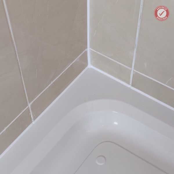 a white bath tub sitting next to a tiled wall in a bathroom with beige walls