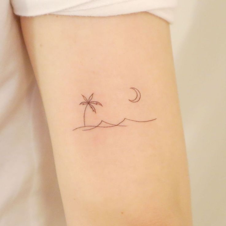 a small palm tree and moon tattoo on the arm