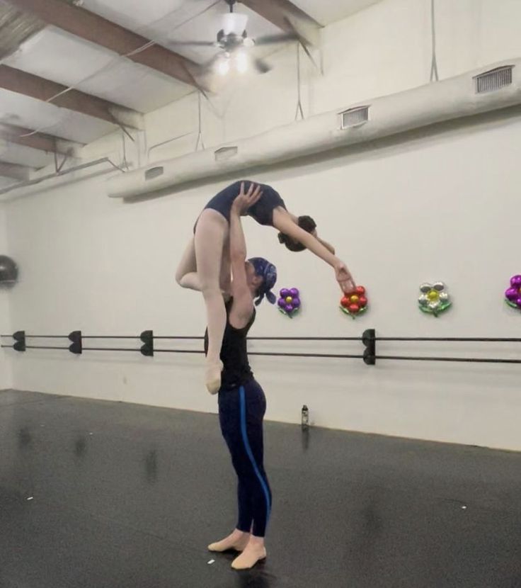 two people are doing acrobatic tricks in an empty room with flowers on the wall