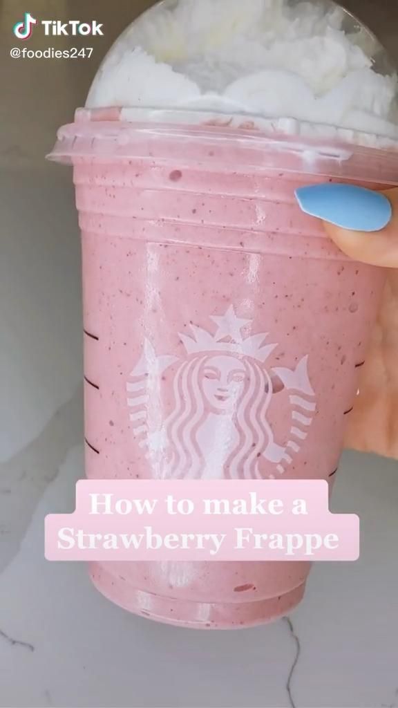 a hand holding a pink starbucks drink with whipped cream on top and the words how to make a strawberry frappe