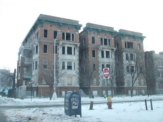 an old brick building with snow on the ground and street signs in front of it