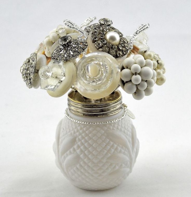 a white vase filled with lots of different types of beads and flowers on top of a table