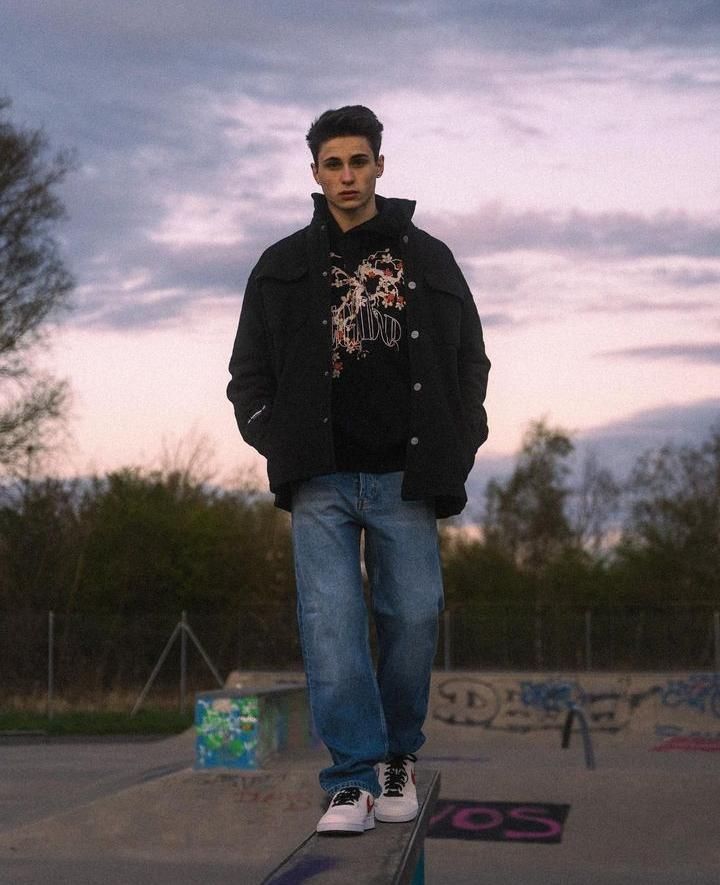 a young man riding a skateboard on top of a metal rail at a skate park