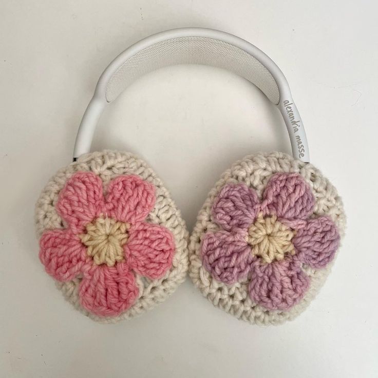 two crocheted flower headphones sitting on top of a white table next to each other