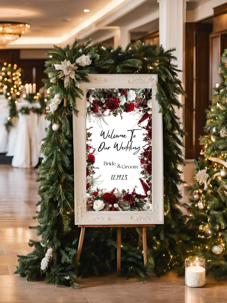 a sign that says welcome to the wedding with flowers and greenery on it in front of christmas trees