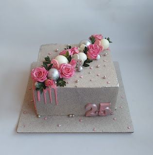 a birthday cake decorated with pink roses and silver decorations on a white tablecloth background