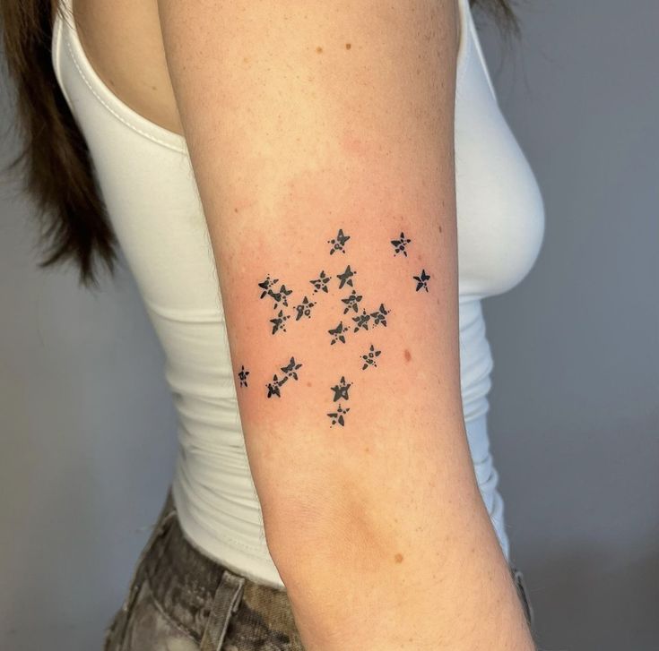 a woman's arm with small stars tattoo on the back of her left arm